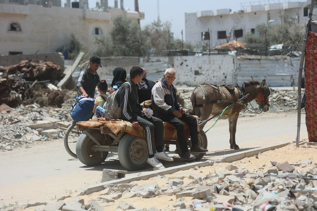 Una familia desplazada viaja en un carro tirado por un burro cargado con sus pertenencias.